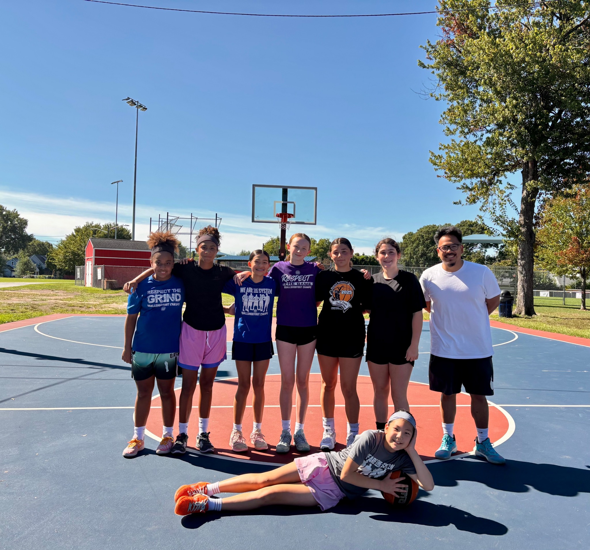 Team Sharp North players and coach on an outdoor basketball court
